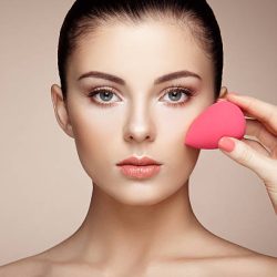 Makeup artist applies skintone. Beautiful woman face. Perfect makeup. Skincare foundation. Sponge makeup artist